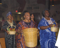 Symbolic gifts are brought forward during the offertory procession by, from left, Almaz Kifiu of Eletria, Africa, and Amanda Strong and Loyce Moore of Holy Angels Parish in Indianapolis.