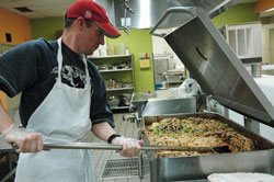 Volunteer Tim Barbour of Indianapolis stirs about 600 servings of spaghetti in a 35-gallon tilt skillet at the Second Helpings production kitchen. St. Joan of Arc parishioner Nora Spitznogle of Indianapolis, director of operations for Second Helpings, said “everything happens on a giant scale here.” (Photo by Mary Ann Wyand) 