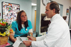 Dr. Thomas Brown, an obstetrician and gynecologist, speaks on March 19 with medical assistant Emily Linville at his office in Greensburg. Brown, a member of St. Louis Parish in Batesville, is a natural family planning-only doctor who has chosen not to prescribe hormonal birth control for the purpose of preventing pregnancy. Linville is a member of St. Nicholas Parish in Ripley County. (Photo by Sean Gallagher) 