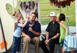 Painting faces always adds a festive touch at parish festivals—a touch experienced by television reporter Keith Kaiser and Father H. Michael Hilderbrand, pastor, during the “Knobs Fest” at St. Mary-of-the-Knobs Parish in Floyd County in June of 2011. Kaiser and Father Hilderbrand benefited from the artistic talents of young parishioners Zoe Libs, left, and Chloe Sprigler. (Submitted photo)