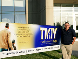 Aaron Hyre stands with a banner promoting “That Man Is You!” at St. Simon the Apostle Parish in Indianapolis. The new program hopes to make Catholic men grow stronger in their faith. (Submitted photo)