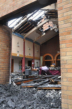 Overcast sunlight filters through the gaps of the burned roof onto the ashes and clutter of St. Monica Parish’s narthex on Sept. 9. Fire destroyed the narthex of the northwest side Indianapolis church earlier that morning. (Photo by Natalie Hoefer)