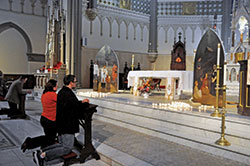 People kneel in prayer on Nov. 2 in St. John the Evangelist Church in Indianapolis before two paintings that the downtown parish commissioned. They portray St. Francis Xavier and St. Theodora Guérin, the archdiocese’s two patron saints. Father Rick Nagel, St. John’s pastor, blessed the paintings created by parishioner Michael McCarthy during an All Souls Day concert of Gabriel Faure’s “Requiem.” (Photo by Sean Gallagher)