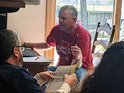 Therese Brandon, left, and Father Joseph Moriarty visit their father, Patrick Moriarty, on April 30 through the window of their father’s room at the St. Paul Hermitage retirement community in Beech Grove. For more than two months, visitors have not been allowed except for end-of-life situations to help protect the residents and staff members from the coronavirus. (Photo by Sean Gallagher)