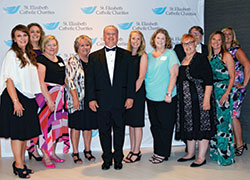 Mark Casper, executive director of St. Elizabeth Catholic Charities in New Albany, center, smiles with his staff during the organization’s fundraising gala on June 24 in Louisville, Ky. (Photo by Natalie Hoefer)